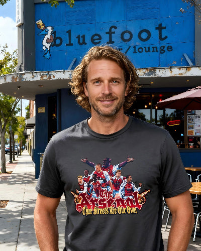 The Arsenal Tifo “These Streets Are Our Own” tee by Unruly Thread — mural-style Arsenal legends across decades on the chest, front view.