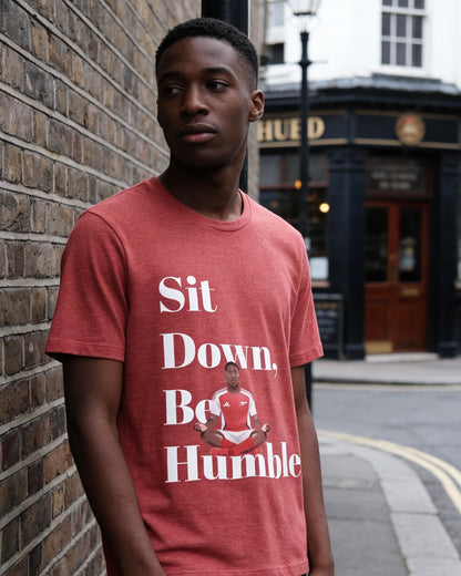 Heather red Sit Down, Be Humble Lewis-Skelly Arsenal tee by Unruly Thread — meditation pose and stacked serif text across the chest.